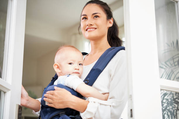 istock Cheerful woman with baby opening window 1153250024