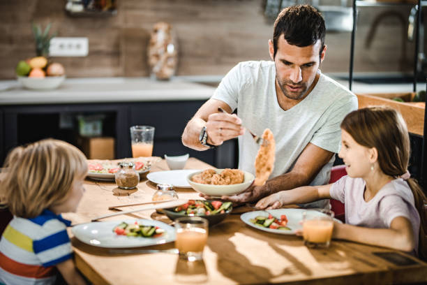istock Young father having lunch with his kids at dining table. 1153250561