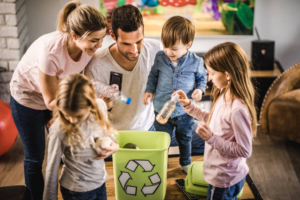família nova que recicl o lixo em um escaninho de recicl em casa. - recycling recycling symbol environmentalist people - fotografias e filmes do acervo