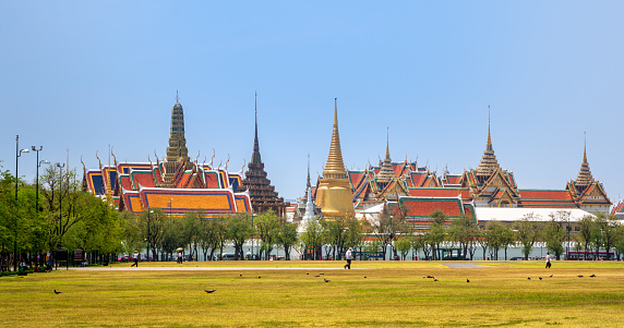 Bangkok, Thailand, March 2013 The Grand Palace, Wat pra kaew with walking people, green grass and blue sky, front view