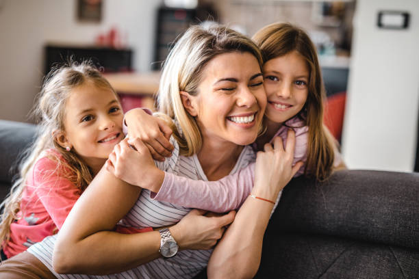 istock Affectionate mother and her small daughters embracing at home. 1153252145
