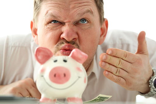 Funny businessman smelling scent of money from piggybank portrait