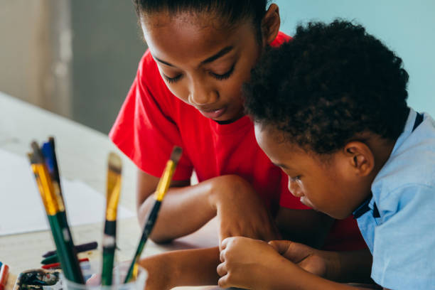 African American kids drawing and painting Closeup of elementary African American kids creatively drawing and painting with brushes and crayon - children creative education concept black african girls pictures stock pictures, royalty-free photos & images