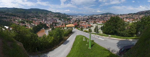 Sarajevo, Bosnia and Herzegovina, Western Balkans - July 8, 2018: aerial view of the skyline of the capital Sarajevo, surrounded by the Dinaric Alps and situated along the Miljacka River, seen from the top of Zuta Tabija (Yellow Fortress) sarajevo, bosnia y herzegovina, balcanes occidentales: vista aérea del horizonte de la capital sarajevo, rodeado por los alpes dináricos y situado a lo largo del río miljacka, visto desde la parte superior de zuta tabija (fortaleza amarilla)