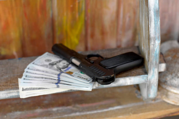 Handgun laid on a pack of us dollars, closeup conceptual shot