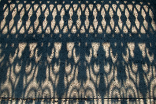 High angle shot of shadow of fence at dusk, fantastic shape of shadow on concrete floor.