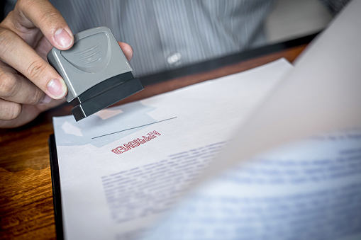 Hands of businessman stamp on paper document to approve business investment contract agreement.