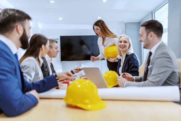 istock Young attractive Caucasian female architect preparing for presentation. her colleagues sitting at desk. 1153269789