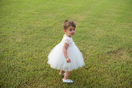 Toddler girl in a white dress on lawn