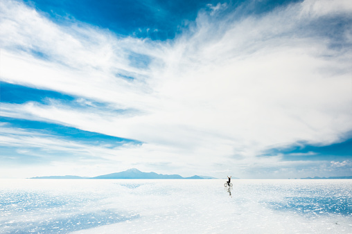 Man riding a bicycle on the Salar de Uyuni salt flat in Bolivia. South America landscapes