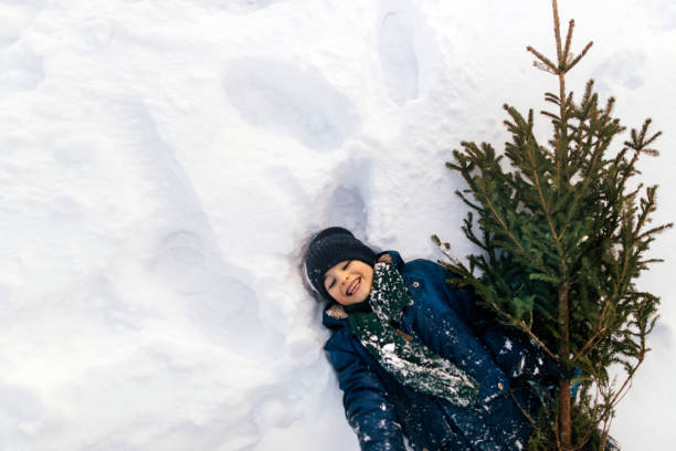 Teenage boy with pet having fun in winter with snow. Cute puppy Cavalier King Charles Spaniel