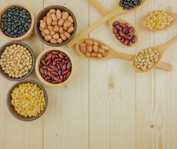 Flat lay,top view assorted beans including red bean,soybeans,black beans,mung beans on brown,beige wooden background with copy space