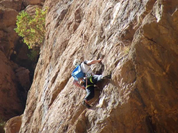 Climber climbing in Todra gorges in Morocco Todra Gorges, Morocco - February 22nd 2019: a solo climber is climbing one of the many beautiful rock walls in Todra Gorges in Morocco sports photography stock pictures, royalty-free photos & images