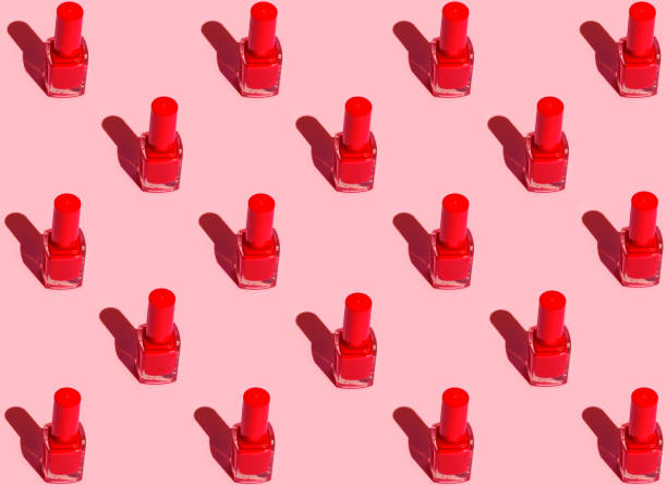 istock Pattern from red nail polish bottles arranged in symmetrical geometric rows on fuchsia pink background. Pop art style with strong sunlight shadows. Fashion make up cosmetics beauty concept 1153276034