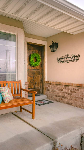 istock Vertical Wooden porch bench with pillows against the shiny front window 1153277219