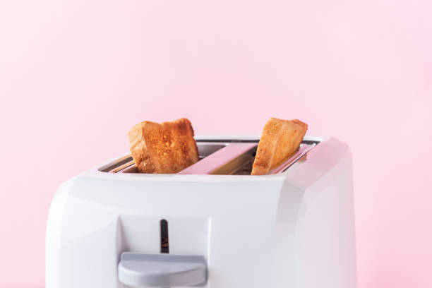 istock White toaster with  roasted toast bread on pink background, close up 1153277377