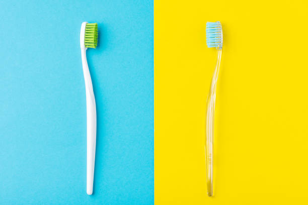 istock Two plastic toothbrushes on a pastel blue and yellow  background, flat lay style 1153277389