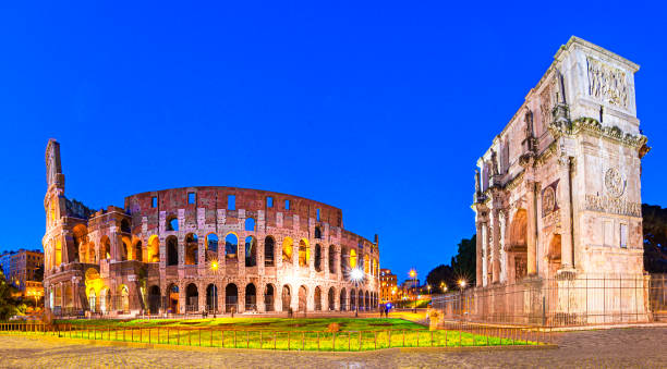 Rome, Italy: Night view of  The Arch of Constantine next to the Colosseum after sunset over a blue sky. Rome, Italy: Night view of  The Arch of Constantine next to the Colosseum after sunset over a blue sky. Colosseum is an elliptical amphitheatre or the Flavian Amphitheatre costantino stock pictures, royalty-free photos & images