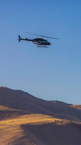 istock Vertical Helicopter flying over an immense mountain with clear blue sky background 1153286482