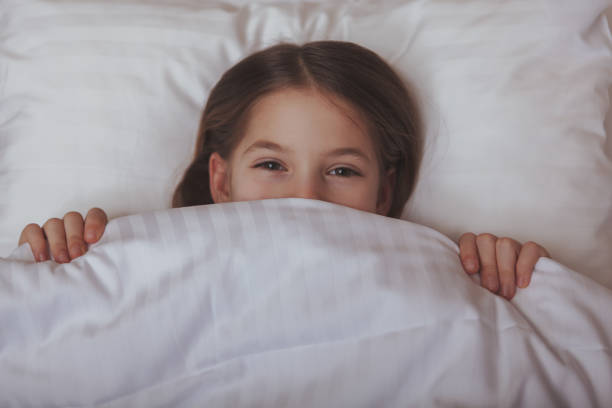 istock Charming young girl lying in bed at home 1153292699