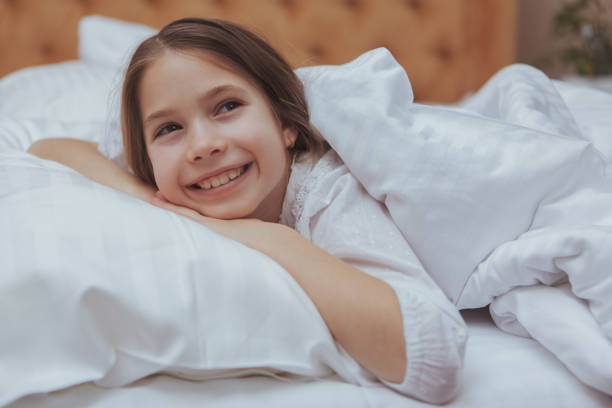 istock Charming young girl lying in bed at home 1153292714