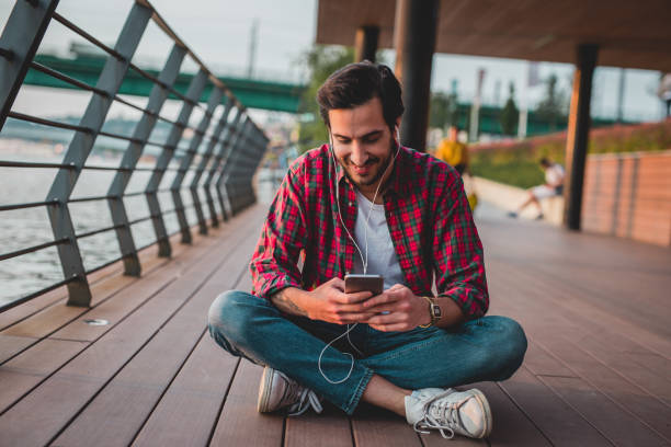 istock a young man uses smartphone while sitting outdoor 1153293766