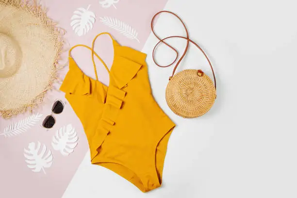 Photo of Fashion bamboo bag and sunglass, straw hat and swimsuit. Flat lay, top view. Summer Vacation concept.