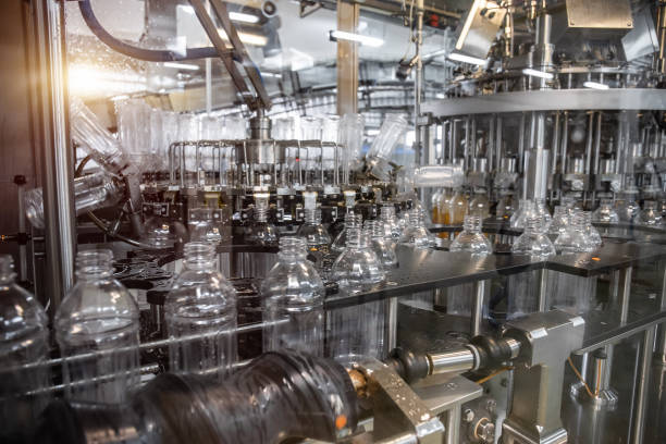 istock Plastic bottles inside industrial machine conveyor line or belt preparing for filling with drink. Water and juice bottling plant 1153299921