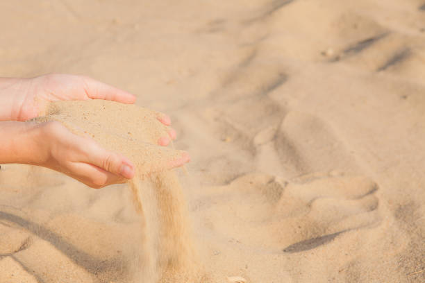 istock Sand flowing through the woman's hands on the beach 1153304886