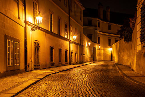 Narrow cobbled street in old medieval town with illuminated houses by vintage street lamps, Novy svet, Prague, Czech Republic. Night shot.