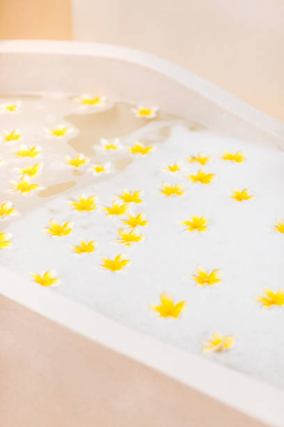 istock Bathtub with foam bubbles and yellow flowers close-up 1153306972