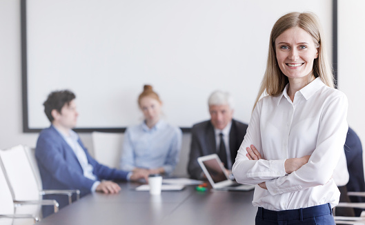 Portrait of beautiful young businessman in front of her team in office