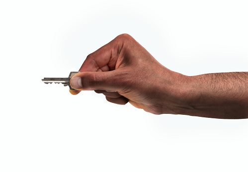 Cropped shot of an unrecognizable man hand holding a home key ready to open the door isolated on a white background