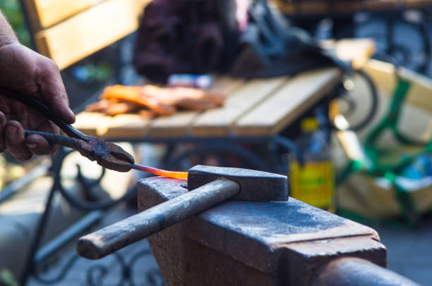 istock blacksmith performs the forging of hot glowing metal on the anvil 1153315935