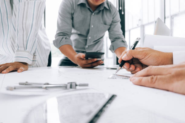istock engineers pointing to building on blueprint to drawing design building Project in office, construction concept. Engineer concept 1153317074
