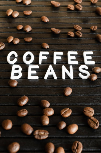 istock White lettering coffee beans and coffee seeds on black background under tilt. 1153317255
