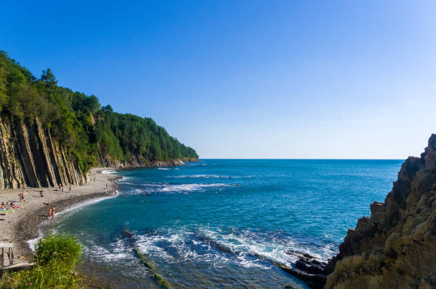sea landscape is a pebbly beach with waves in white foam, a beautiful sky with clouds, a warm summer day