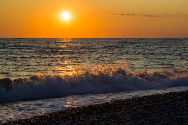 istock Amazing sea sunset on the pebble beach, the sun, waves, clouds 1153317991