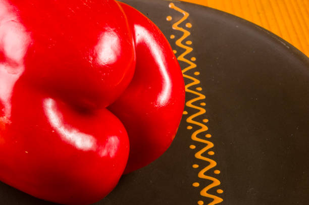 a freshest red paprika, bell pepper in ceramic plate on wooden background, close up