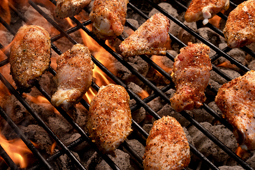 Hot and spicy grilled buffalo chicken wings cooking on a grill with flames