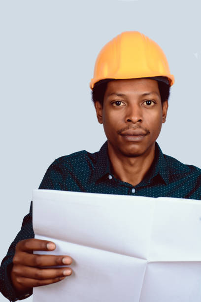 istock Afro american architect in hard hat with blueprint. 1153333963