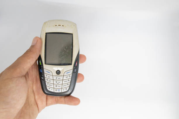 istock Finger holding old generation of mobile phone with white isolate die cut background. Traditional cellphone during 1995-2010 century. 1153335233
