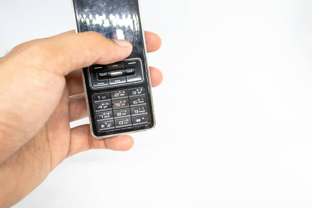 istock Finger holding old generation of mobile phone with white isolate die cut background. Traditional cellphone during 1995-2010 century. 1153335235