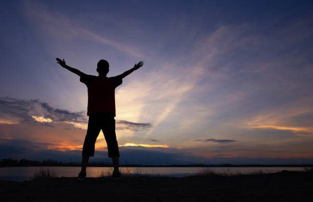 istock silhouette man raise his hand on beautiful sunset 1153346130