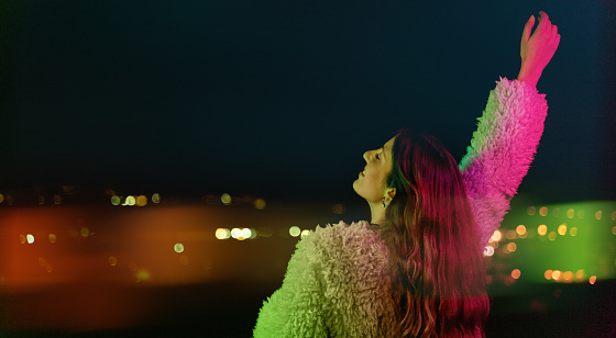 Young woman looking at city lights under colorful light