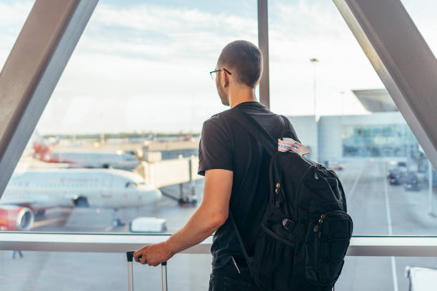 istock Man in airport near gate windows at planes on runway. 1153356681