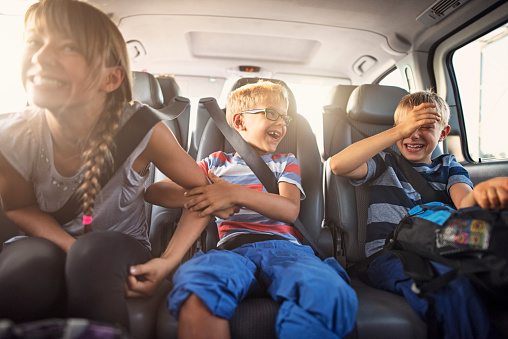 Happy playful kids travelling by car