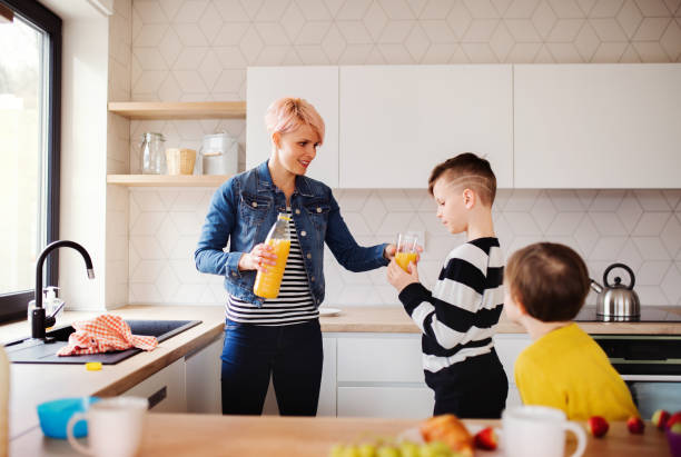 istock A young woman with two children drinking juice in a kitchen. 1153364177