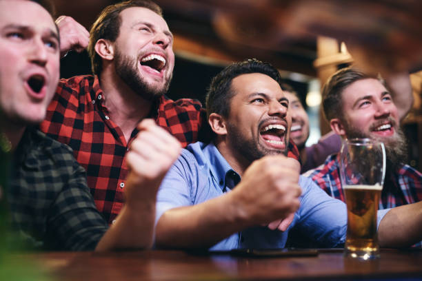 Men watching television and cheering for team Men watching television and cheering for team pub stock pictures, royalty-free photos & images