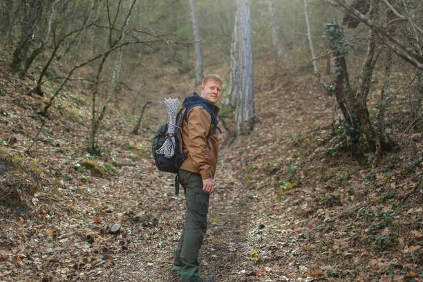 istock Man stands sideways and looks at the camera in a forest 1153368402